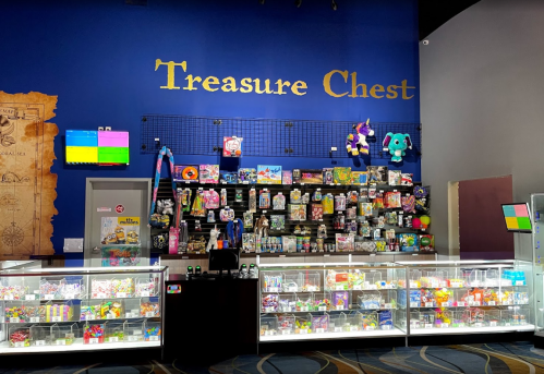 A colorful display of toys and games in a shop called "Treasure Chest," with a blue wall and bright lighting.