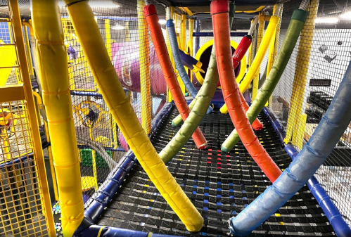 Colorful indoor play structure with soft, padded tubes and nets, designed for children's play and exploration.