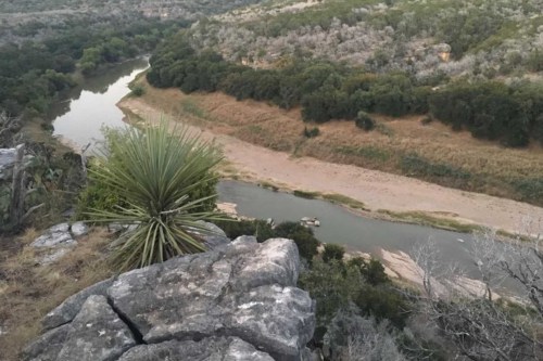 A scenic view of a winding river surrounded by rocky terrain and lush greenery, captured from a high vantage point.