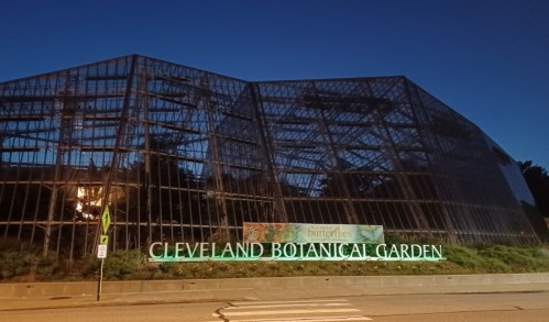 Cleveland Botanical Garden at night, featuring a large glass structure and illuminated sign.