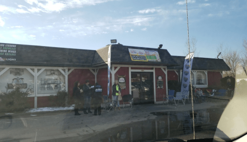 A red building with a sloped roof, featuring a sign for "Social Hour Thursdays" and people gathered outside.