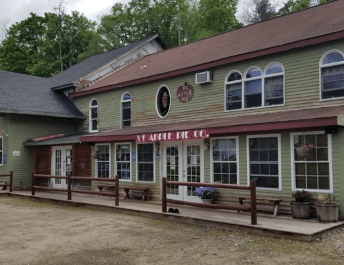 Exterior of the VT Apple Pie Co. building, featuring large windows and a welcoming porch with benches.