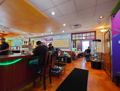 Interior of a vibrant restaurant with colorful decor, a bar area, and patrons dining in the background.