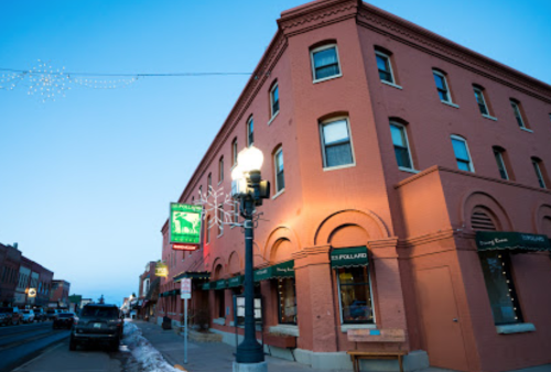 Historic pink building with festive lights, street lamps, and parked cars in a winter setting.