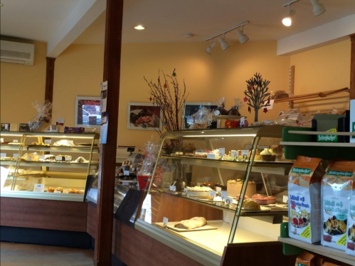 A cozy bakery interior featuring display cases filled with various pastries and desserts. Warm, inviting atmosphere.