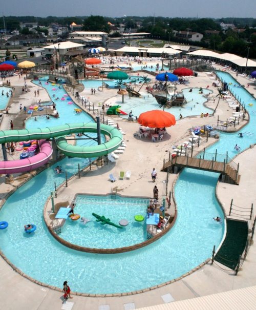 Aerial view of a vibrant water park featuring slides, pools, and colorful umbrellas with visitors enjoying the attractions.