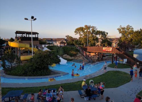 A vibrant water park scene with slides, a lazy river, and families enjoying the sun and water activities.