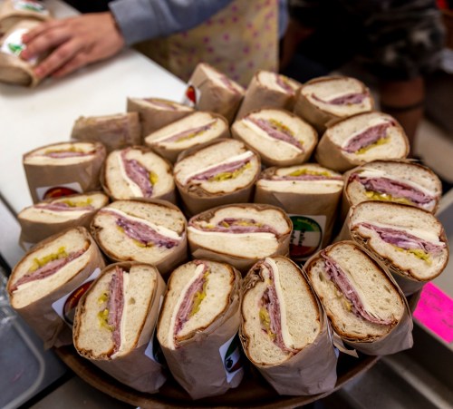 A platter of neatly wrapped sandwiches with layers of meat and condiments, ready to be served.