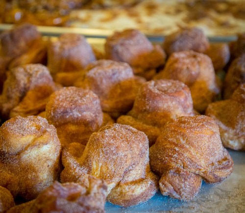 A close-up of golden-brown, sugar-coated pastries arranged closely together on a tray.