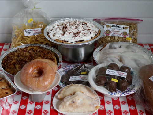 A variety of baked goods including pies, donuts, and granola displayed on a festive tablecloth.