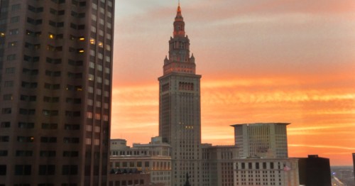 Cleveland skyline at sunset, featuring the Key Tower with vibrant orange and pink hues in the sky.