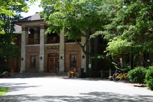 A brick building with columns, surrounded by trees and greenery, featuring a sign that reads "Lodge Run Inn."