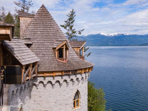 A scenic view of a stone castle turret overlooking a lake with mountains in the background.