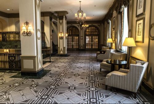 Elegant hotel lobby featuring patterned flooring, striped armchairs, and decorative lighting.