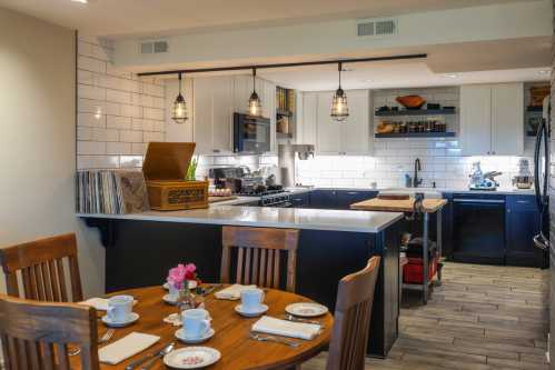 A cozy kitchen with a wooden dining table set for breakfast, featuring modern appliances and stylish decor.