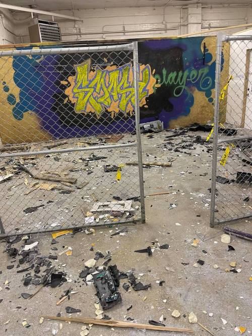 A messy, abandoned room with a colorful graffiti mural and debris scattered on the floor.