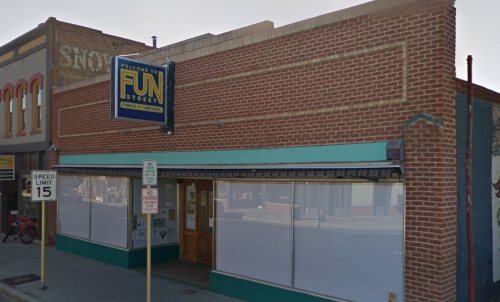 A brick building with a sign reading "Welcome to Fun Street" and large windows covered by white shades.