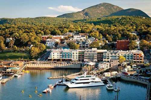 A scenic waterfront view of a town with colorful buildings, boats, and a mountain backdrop under a clear sky.