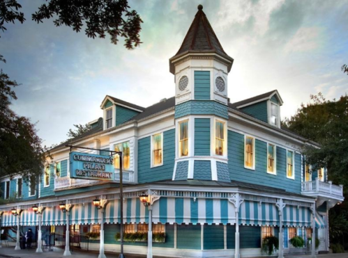 A charming blue and white restaurant with a tower, featuring striped awnings and warm, inviting windows.