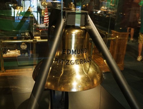 Close-up of the bell from the Edmund Fitzgerald, displayed in a glass case with a blurred background.