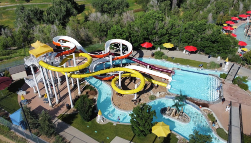 Aerial view of a water park featuring colorful slides, a lazy river, and shaded seating areas.