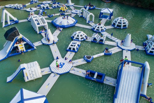 Aerial view of a large inflatable water park with various structures and people enjoying activities on the water.