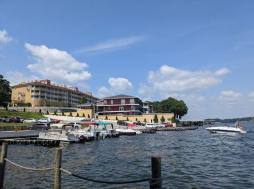 A scenic view of a marina with boats, a hotel, and blue skies with fluffy clouds.