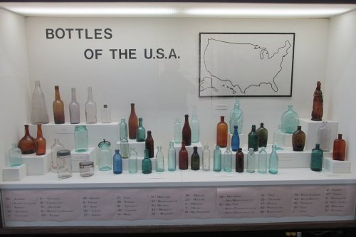 Display of various vintage bottles from the USA, arranged on white pedestals with a map in the background.