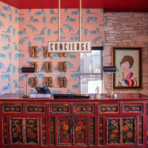 A colorful hotel concierge desk with a tiger-patterned wall, decorative items, and a framed portrait.