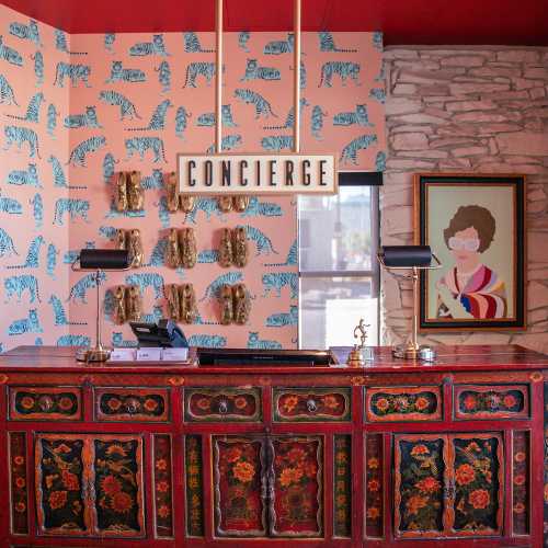 A colorful hotel concierge desk with a tiger-patterned wall, decorative items, and a framed portrait.