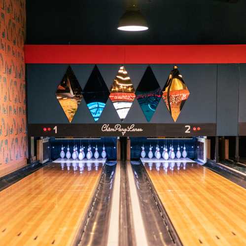 A bowling alley with two lanes, featuring colorful diamond-shaped decor and neatly arranged bowling pins.