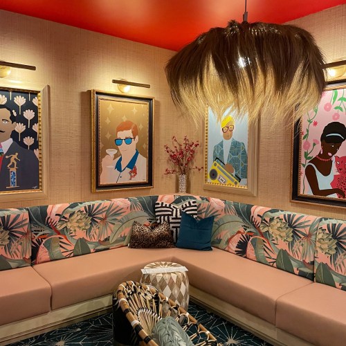 A cozy lounge area with tropical-themed seating, colorful artwork on the walls, and a stylish pendant light.