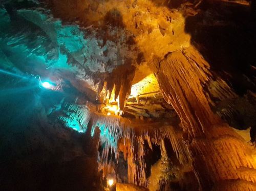 Stalactites and stalagmites illuminated by colorful lights in a cave, showcasing unique rock formations.