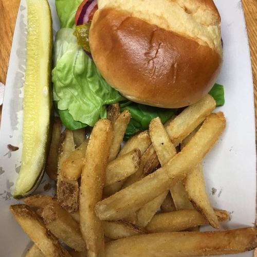 A plate with a sandwich featuring lettuce, onion, and a pickle, accompanied by a side of golden French fries.