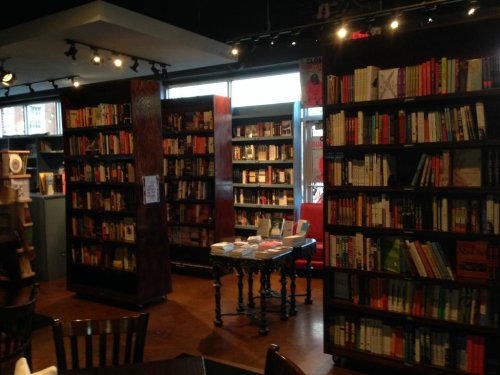 A cozy bookstore interior with wooden shelves filled with books and a small table in the center.