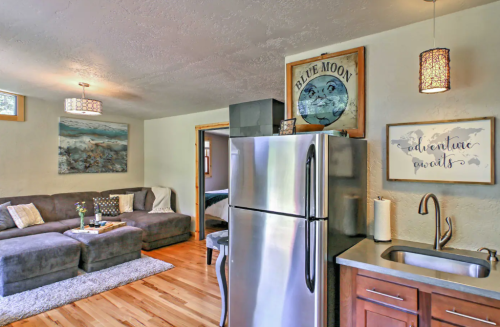 Cozy living room with a gray sectional sofa, modern decor, and a stainless steel fridge in a bright, inviting space.