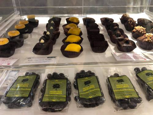 A display case filled with assorted chocolates and hazelnuts, including truffles and chocolate-covered treats.