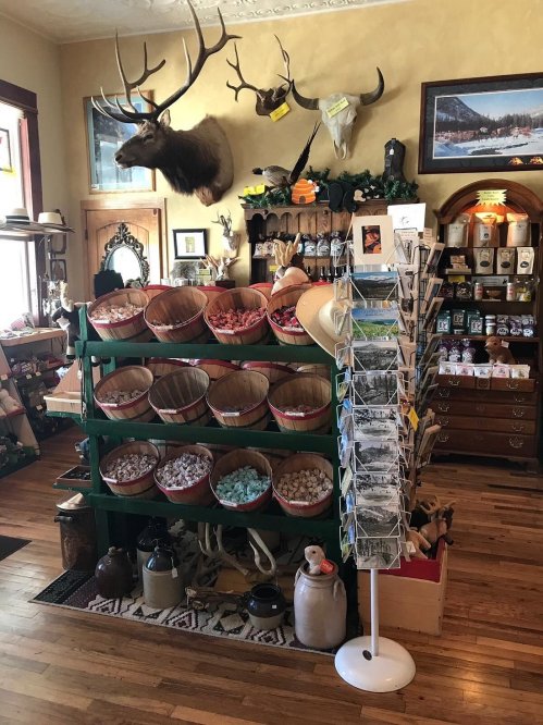 A cozy shop interior featuring baskets of colorful items, mounted animal heads, and various rustic decor.