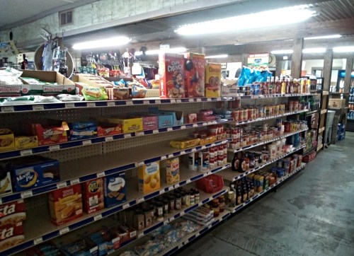 A grocery store aisle filled with various packaged foods, snacks, and condiments on shelves.