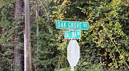 Street signs for Oak Grove Rd and Kali Oka Rd surrounded by greenery.