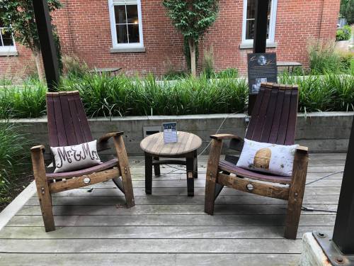 Two wooden chairs with cushions labeled "Mr. & Mrs." sit beside a small round table in a garden setting.