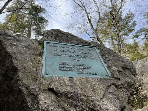 A bronze plaque on a rock at Purgatory Chasm State Reservation, detailing its establishment in 1906.