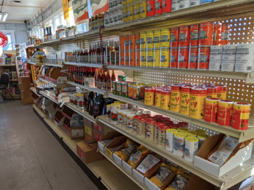 A grocery store aisle filled with various canned goods, sauces, and packaged items on shelves.