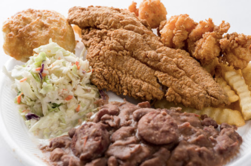 A plate of fried fish, shrimp, coleslaw, French fries, and beans, served with a biscuit.