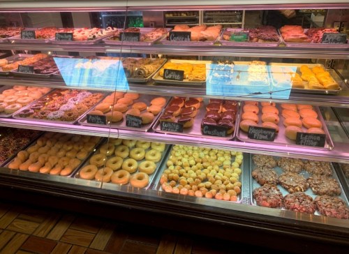 A display case filled with various donuts and pastries, including glazed, filled, and specialty options.
