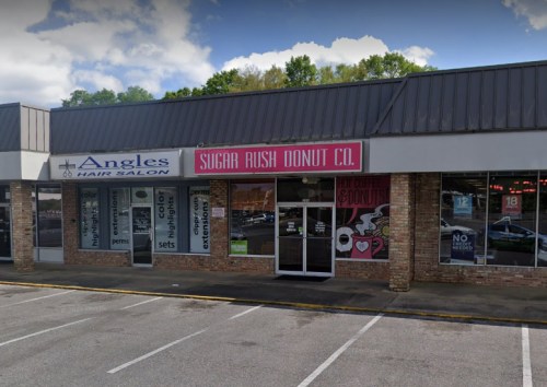 Exterior view of a shopping plaza featuring Angles Hair Salon and Sugar Rush Donut Co. with a clear blue sky above.