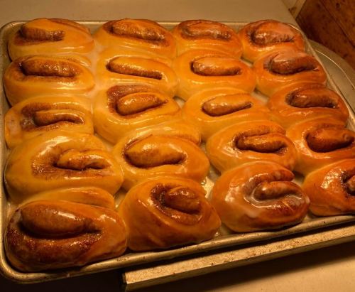 A tray of freshly baked cinnamon rolls with a glossy glaze, arranged neatly in rows.