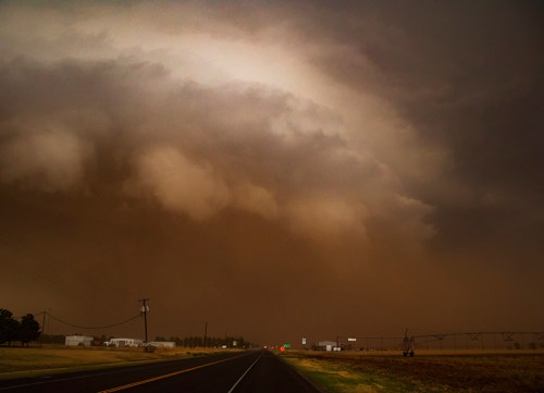 Dark, ominous clouds loom over a deserted road, hinting at an approaching storm.