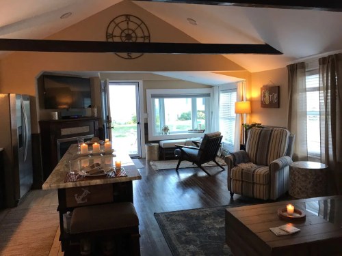 Cozy living space with a striped chair, candles, and large windows overlooking a scenic view. Warm, inviting atmosphere.