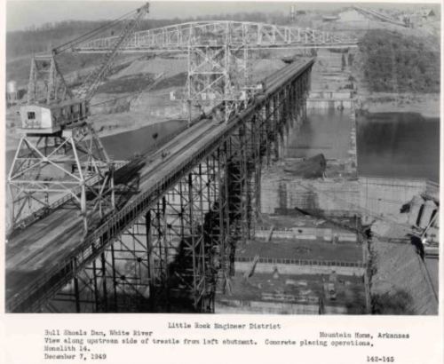 Black and white photo of the Bull Shoals Dam construction on the White River, showing cranes and concrete placement operations.